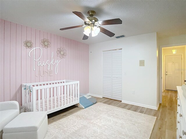 9425 Sterling Ln, Port Richey, FL 34668 - bedroom featuring wood finished floors, a closet, a ceiling fan, a nursery area, and a textured ceiling