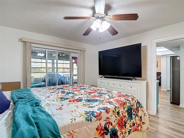 9425 Sterling Ln, Port Richey, FL 34668 - bedroom featuring access to exterior, light wood-style flooring, a textured ceiling, and a ceiling fan