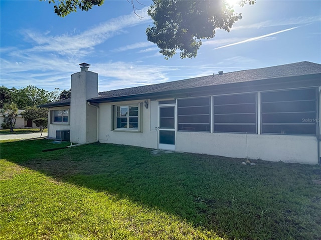 9425 Sterling Ln, Port Richey, FL 34668 - rear view of house with a chimney, a lawn, and stucco siding
