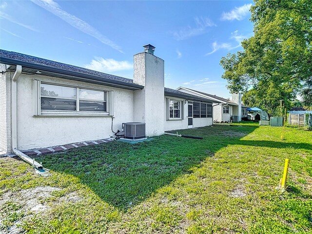 9425 Sterling Ln, Port Richey, FL 34668 - rear view of property with stucco siding, a yard, and a chimney