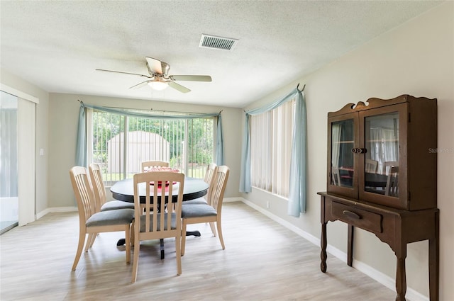 10600 Oleander Dr, Port Richey, FL 34668 - dining area with light wood-type flooring, ceiling fan, and a textured ceiling