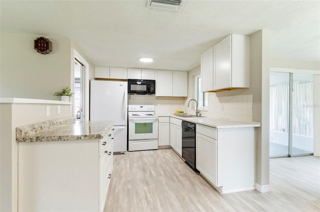 10600 Oleander Dr, Port Richey, FL 34668 - kitchen with black appliances, light wood-type flooring, backsplash, and white cabinets