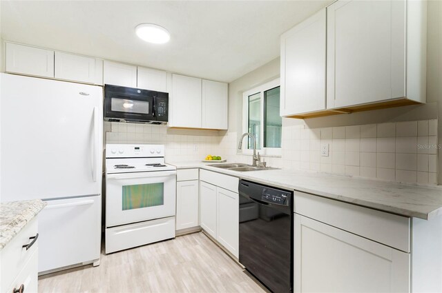 10600 Oleander Dr, Port Richey, FL 34668 - kitchen featuring black appliances, decorative backsplash, light wood-style floors, and white cabinets