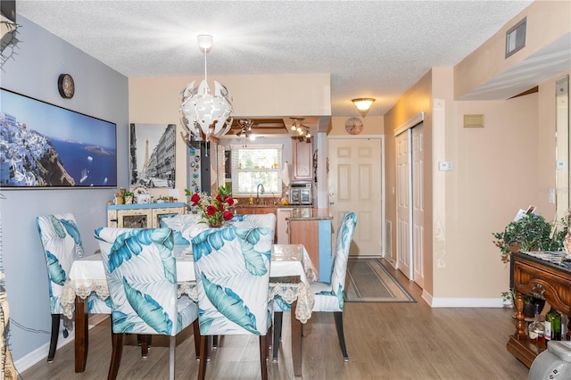 4939 Floramar Ter Unit 203, New Port Richey, FL 34652 - dining area with a chandelier, wood finished floors, and a textured ceiling