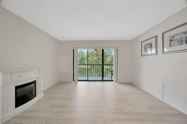 3134 Lake Pine Way Unit F2, Tarpon Springs, FL 34688 - unfurnished living room with light wood-style floors and a glass covered fireplace