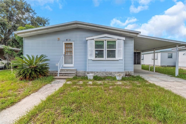 5641 Columbia Dr, New Port Richey, FL 34652 - manufactured / mobile home featuring entry steps, driveway, a front lawn, and a carport
