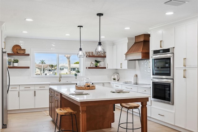 5348 Lawrence Ln, New Port Richey, FL 34652 - kitchen with open shelves, custom range hood, appliances with stainless steel finishes, a breakfast bar area, and light countertops