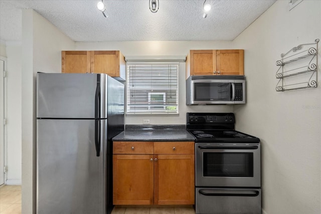 2500 Winding Creek Blvd Unit G106, Clearwater, FL 33761 - kitchen featuring appliances with stainless steel finishes, dark countertops, brown cabinets, and a textured ceiling