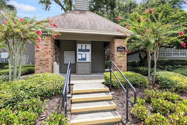 2500 Winding Creek Blvd Unit G106, Clearwater, FL 33761 - view of front of property with a shingled roof, brick siding, and a chimney