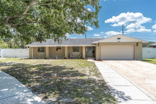 2954 Leisure Ct, Dunedin, FL 34698 - ranch-style home featuring a gate, brick siding, and a garage