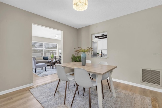 2954 Leisure Ct, Dunedin, FL 34698 - dining space featuring light wood-style floors, a chandelier, and a textured ceiling