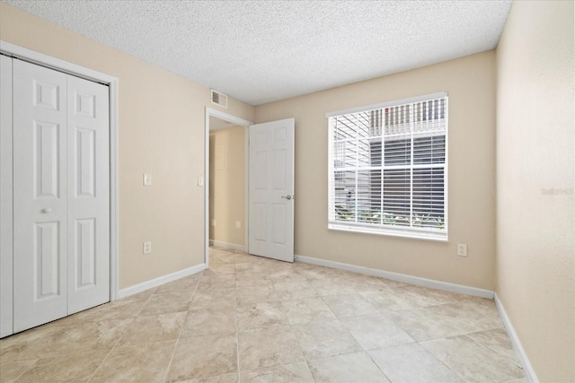 2500 Winding Creek Blvd Unit I106, Clearwater, FL 33761 - unfurnished bedroom with a textured ceiling, a closet, and light tile patterned flooring