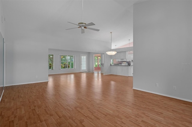 7445 Nature Walk Dr, Spring Hill, FL 34606 - unfurnished living room with high vaulted ceiling, light wood-style flooring, ceiling fan, and a chandelier