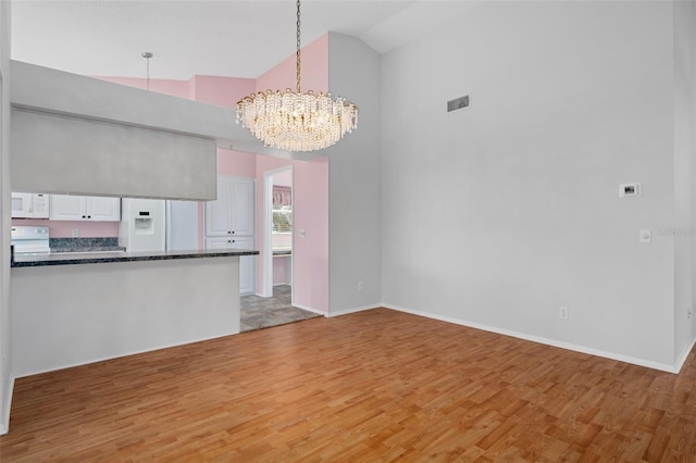 7445 Nature Walk Dr, Spring Hill, FL 34606 - kitchen with white appliances, a chandelier, dark countertops, high vaulted ceiling, and white cabinets
