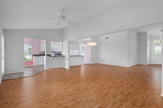 7445 Nature Walk Dr, Spring Hill, FL 34606 - unfurnished living room with ceiling fan, a chandelier, light wood finished floors, healthy amount of natural light, and high vaulted ceiling