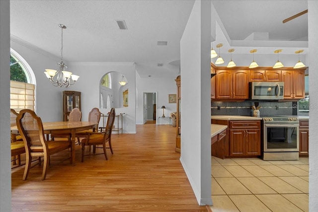 14178 Pullman Dr, Spring Hill, FL 34609 - kitchen with stainless steel appliances, light countertops, light wood finished floors, ornamental molding, and a chandelier