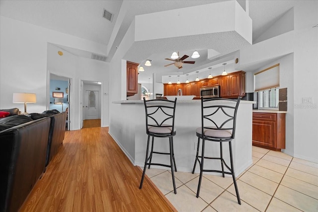 14178 Pullman Dr, Spring Hill, FL 34609 - kitchen with stainless steel microwave, a kitchen breakfast bar, a ceiling fan, a peninsula, and lofted ceiling