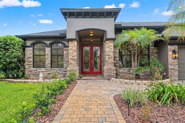 26221 Pheasant Run, Wesley Chapel, FL 33544 - view of exterior entry with french doors, stone siding, a shingled roof, an attached garage, and stucco siding