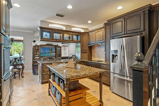 26221 Pheasant Run, Wesley Chapel, FL 33544 - kitchen featuring stainless steel fridge, light tile patterned flooring, a peninsula, dark stone countertops, and decorative backsplash