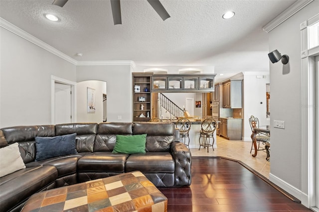 26221 Pheasant Run, Wesley Chapel, FL 33544 - living room featuring a textured ceiling, ceiling fan, stairway, ornamental molding, and light wood-style floors