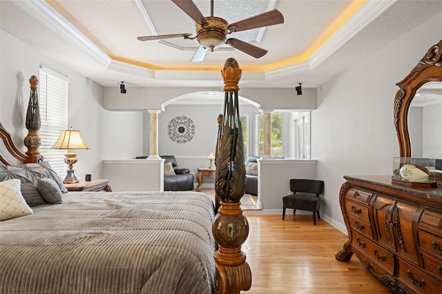 26221 Pheasant Run, Wesley Chapel, FL 33544 - bedroom featuring ornate columns, a raised ceiling, crown molding, light wood finished floors, and arched walkways