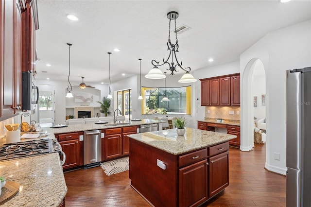 9829 Sorbonne Loop, Seffner, FL 33584 - kitchen featuring appliances with stainless steel finishes, arched walkways, open floor plan, dark wood-type flooring, and ceiling fan