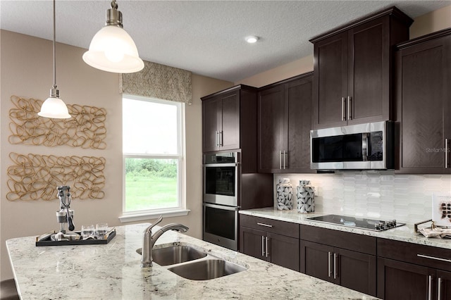 3878 Isle Royal Pl, Apopka, FL 32712 - kitchen featuring appliances with stainless steel finishes, decorative backsplash, pendant lighting, dark brown cabinets, and light stone counters