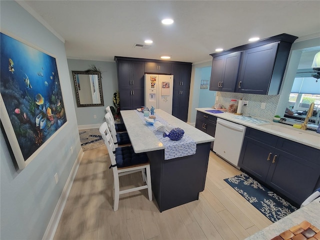 6737 Clark St, Hudson, FL 34667 - kitchen with white appliances, light wood-type flooring, tasteful backsplash, a center island, and light stone countertops