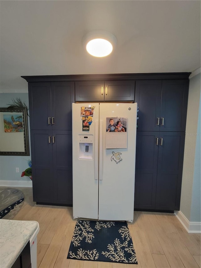 6737 Clark St, Hudson, FL 34667 - kitchen featuring white refrigerator with ice dispenser, light wood-style floors, and blue cabinets