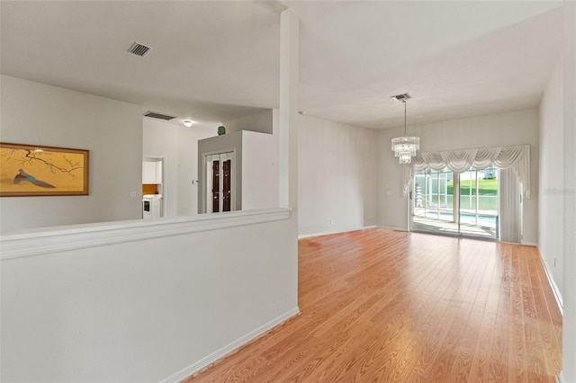 7328 Blue Skies Dr, Spring Hill, FL 34606 - unfurnished room featuring wood finished floors, a chandelier, and washer / clothes dryer