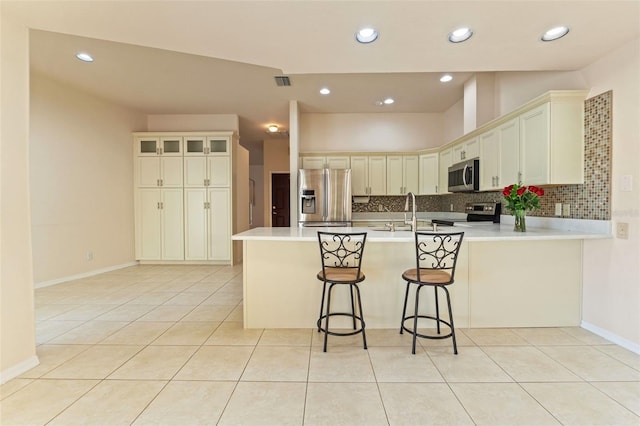 7328 Blue Skies Dr, Spring Hill, FL 34606 - kitchen with stainless steel appliances, a peninsula, backsplash, light countertops, and light tile patterned flooring