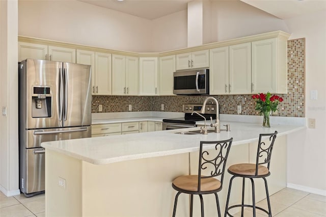 7328 Blue Skies Dr, Spring Hill, FL 34606 - kitchen featuring appliances with stainless steel finishes, a peninsula, light tile patterned floors, a breakfast bar, and decorative backsplash