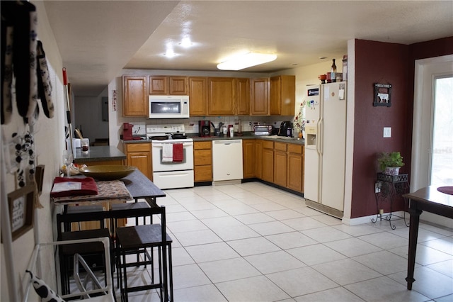 5635 Kimball Rd, Mulberry, FL 33860 - kitchen featuring white appliances, decorative backsplash, light tile patterned flooring, dark countertops, and brown cabinetry