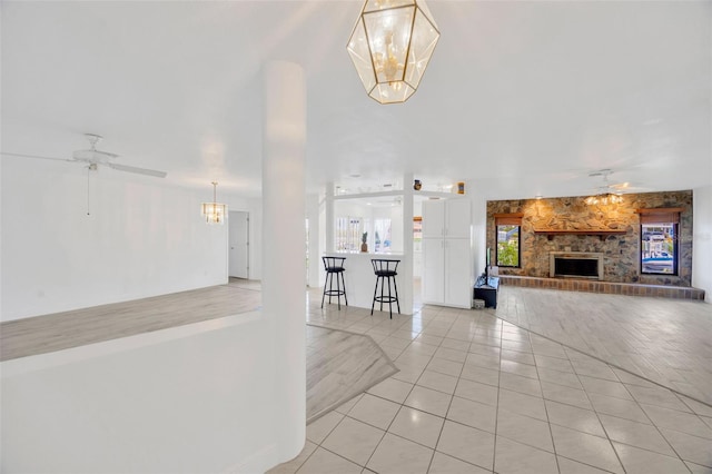 8143 Channel Dr, Port Richey, FL 34668 - unfurnished living room with a ceiling fan, light tile patterned floors, a fireplace, and a chandelier