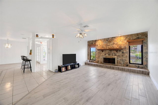 8143 Channel Dr, Port Richey, FL 34668 - living area featuring ceiling fan, a chandelier, a stone fireplace, and light wood-type flooring