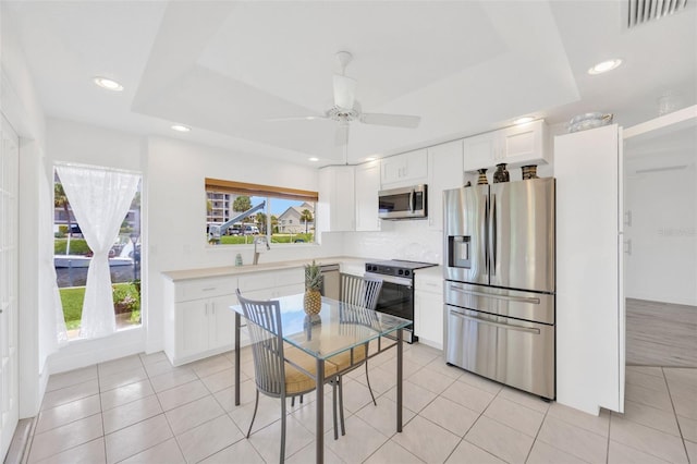 8143 Channel Dr, Port Richey, FL 34668 - kitchen with appliances with stainless steel finishes, a raised ceiling, white cabinetry, a ceiling fan, and recessed lighting