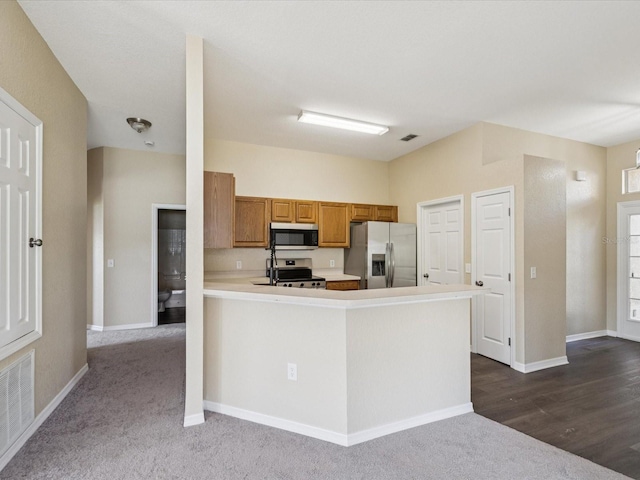 5048 Teather St, Spring Hill, FL 34608 - kitchen with appliances with stainless steel finishes, brown cabinets, light countertops, a peninsula, and dark carpet
