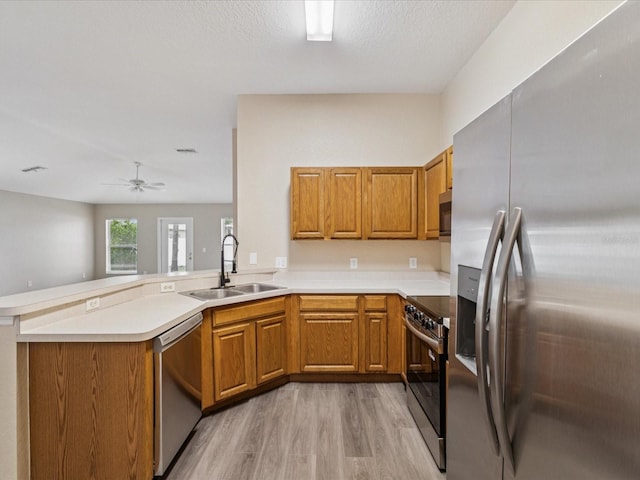 5048 Teather St, Spring Hill, FL 34608 - kitchen featuring appliances with stainless steel finishes, a peninsula, brown cabinetry, and light wood-type flooring