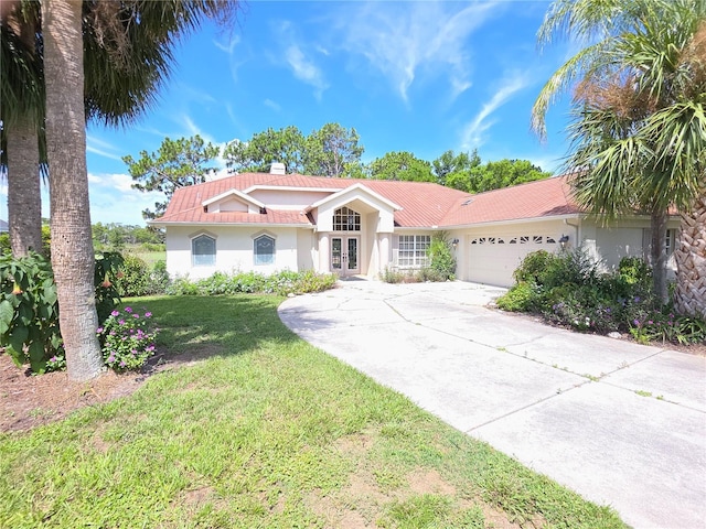 9168 Southern Comfort Ct, Weeki Wachee, FL 34613 - mediterranean / spanish-style home featuring french doors, stucco siding, an attached garage, driveway, and a front yard