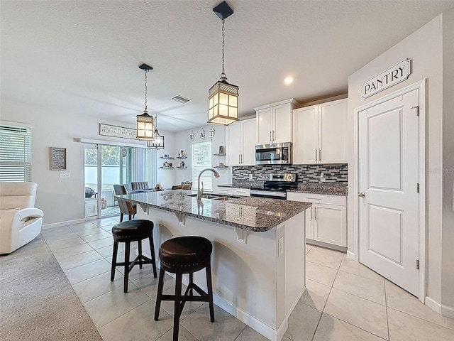 8855 Prairie Creek Dr, New Port Richey, FL 34655 - kitchen with appliances with stainless steel finishes, light tile patterned floors, dark stone countertops, a kitchen breakfast bar, and decorative backsplash