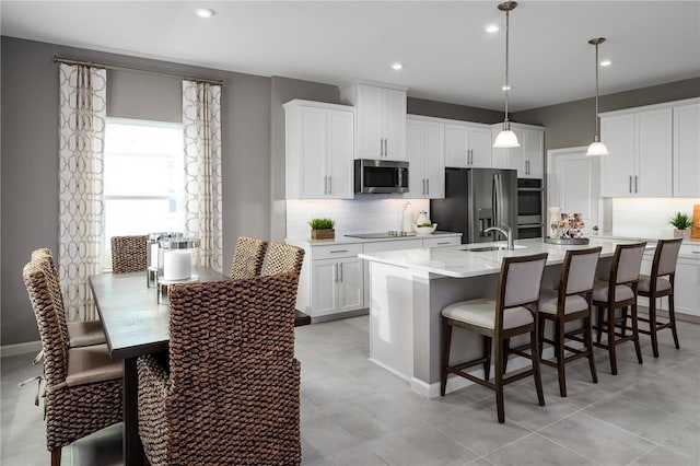 10816 SW 72nd Cir, Ocala, FL 34476 - kitchen featuring stainless steel appliances, tasteful backsplash, light countertops, an island with sink, and white cabinets