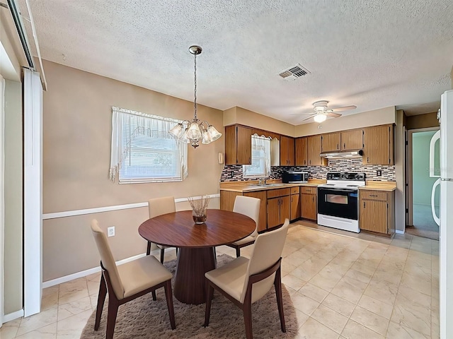 11094 Auburndale St, Spring Hill, FL 34609 - kitchen with white range with electric cooktop, under cabinet range hood, light marble finish floors, tasteful backsplash, and a textured ceiling