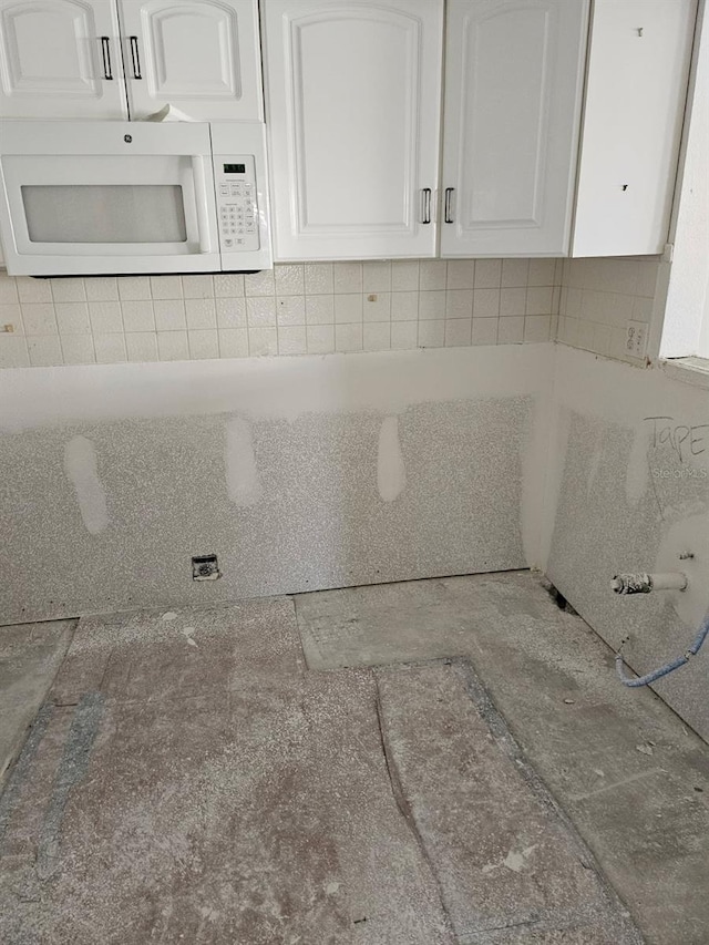4743 Jasper Dr Unit 107, New Port Richey, FL 34652 - kitchen view of white microwave, white cabinetry, and tasteful backsplash