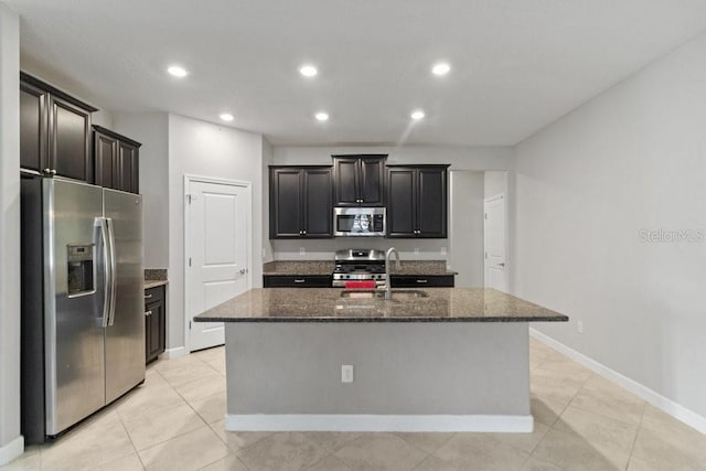 16874 Balance Cv, Land O Lakes, FL 34638 - kitchen with stainless steel appliances, dark stone countertops, recessed lighting, a center island with sink, and light tile patterned flooring