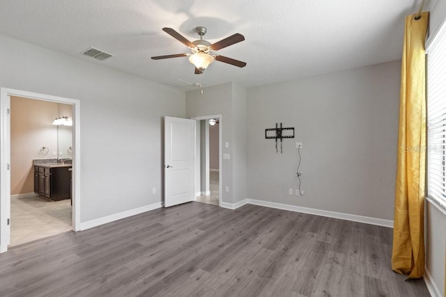 16874 Balance Cv, Land O Lakes, FL 34638 - unfurnished bedroom with dark wood finished floors, ensuite bath, and ceiling fan