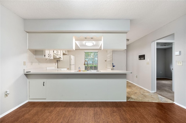 7700 Danube Dr Unit 7700, Hudson, FL 34667 - kitchen featuring wood finished floors, freestanding refrigerator, under cabinet range hood, light countertops, and a peninsula