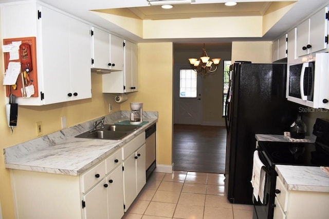 6575 Brambleleaf Dr, Spring Hill, FL 34606 - kitchen with black range with electric cooktop, white microwave, a tray ceiling, a chandelier, and light tile patterned floors