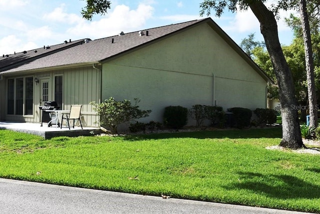 6575 Brambleleaf Dr, Spring Hill, FL 34606 - view of side of property featuring a lawn, a patio, a shingled roof, and board and batten siding
