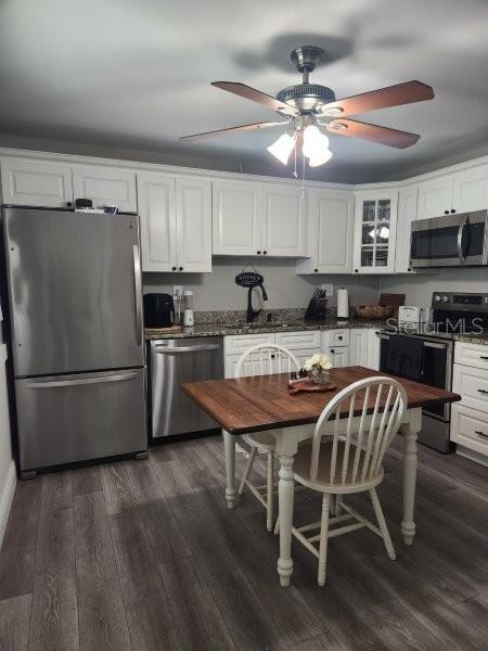 5710 Broadway Ave, New Port Richey, FL 34652 - kitchen featuring appliances with stainless steel finishes, white cabinets, a ceiling fan, and dark wood-type flooring
