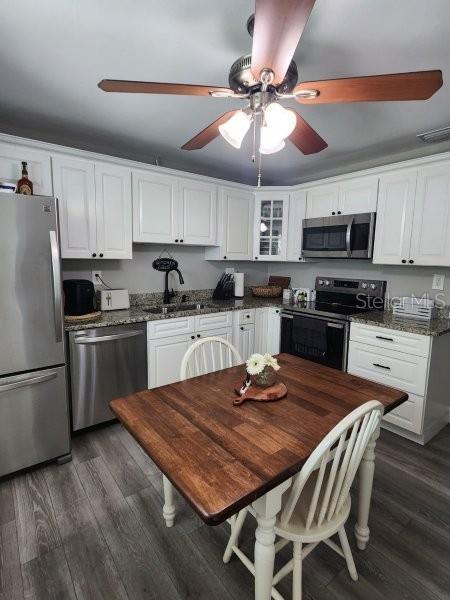 5710 Broadway Ave, New Port Richey, FL 34652 - kitchen with appliances with stainless steel finishes, a ceiling fan, white cabinetry, and dark wood-type flooring